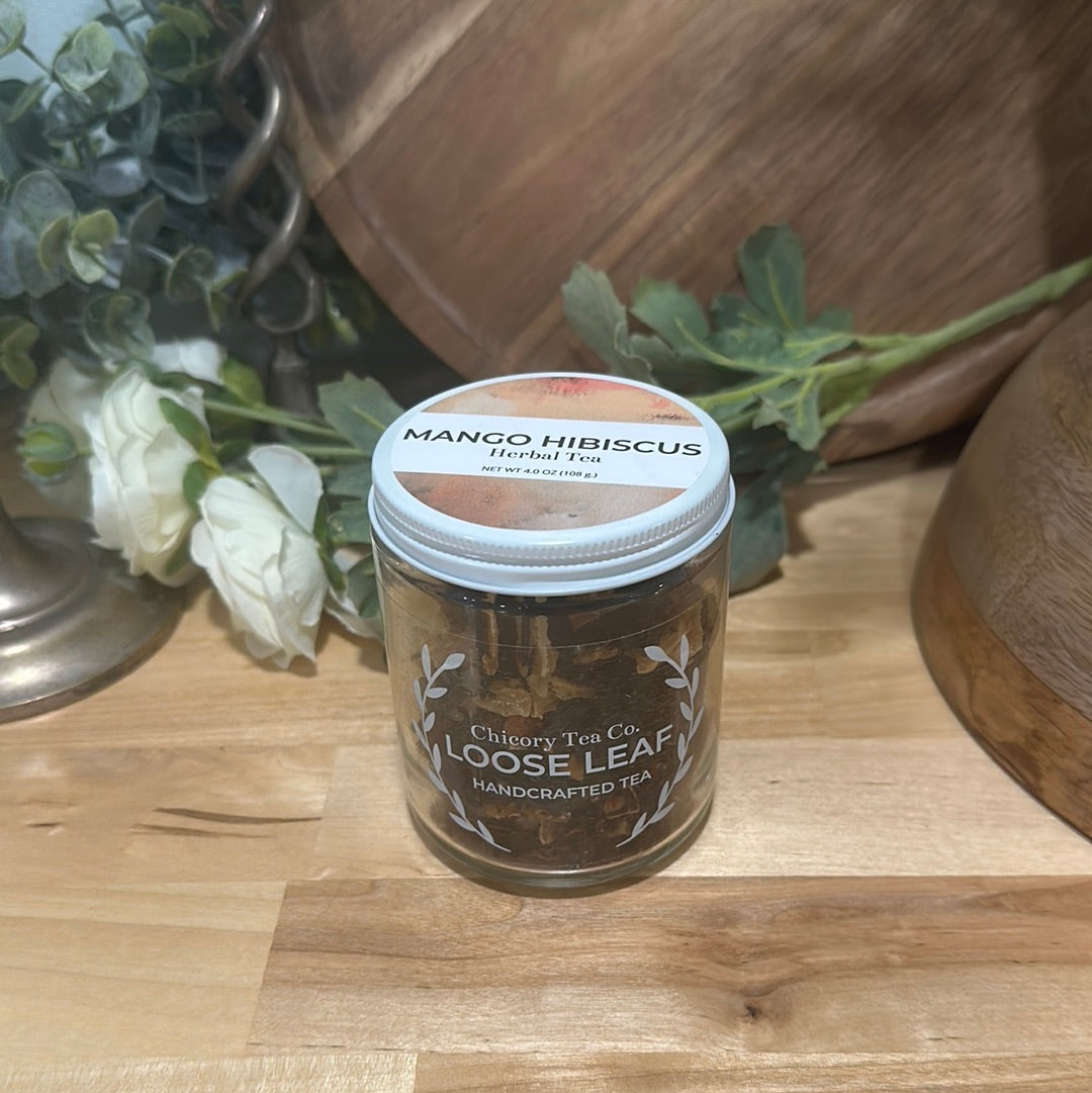 Chicory Tea Co.'s Mango Hibiscus on a wood floor with a vine and a barrel in the background